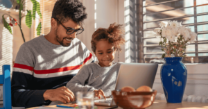 Father and daughter looking at a laptop screen in the kitchen