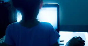 A young girls looking at a laptop screen in the dark