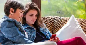 A mother and a daughter look at a phone together