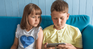 Two children look at a device.