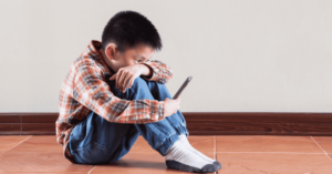 Boy sitting on the floor looking at his smartphone