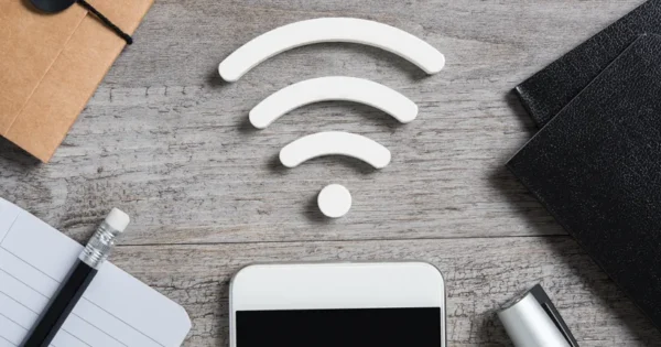 Items on a desk - notepad, diary, folders, pens and a smartphone - and the Wi-Fi connection symbol at the centre