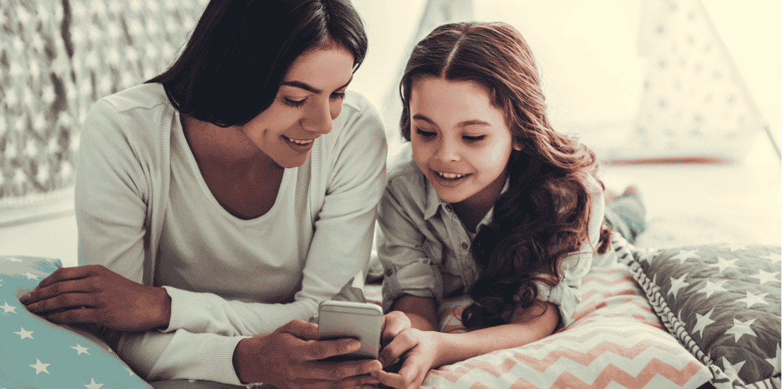 A mum uses a smartphone with her daughter.