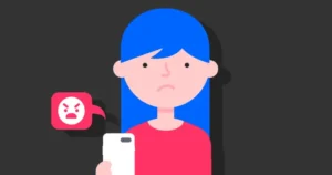 A girl with a sad looking on her face holding a smartphone where she received an angry message from someone