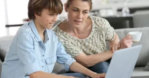 A mum and son look at a laptop together.