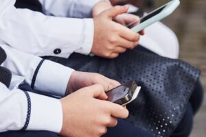 Children use smartphones in school uniforms.