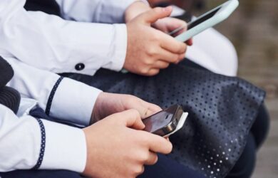 Children use smartphones in school uniforms.