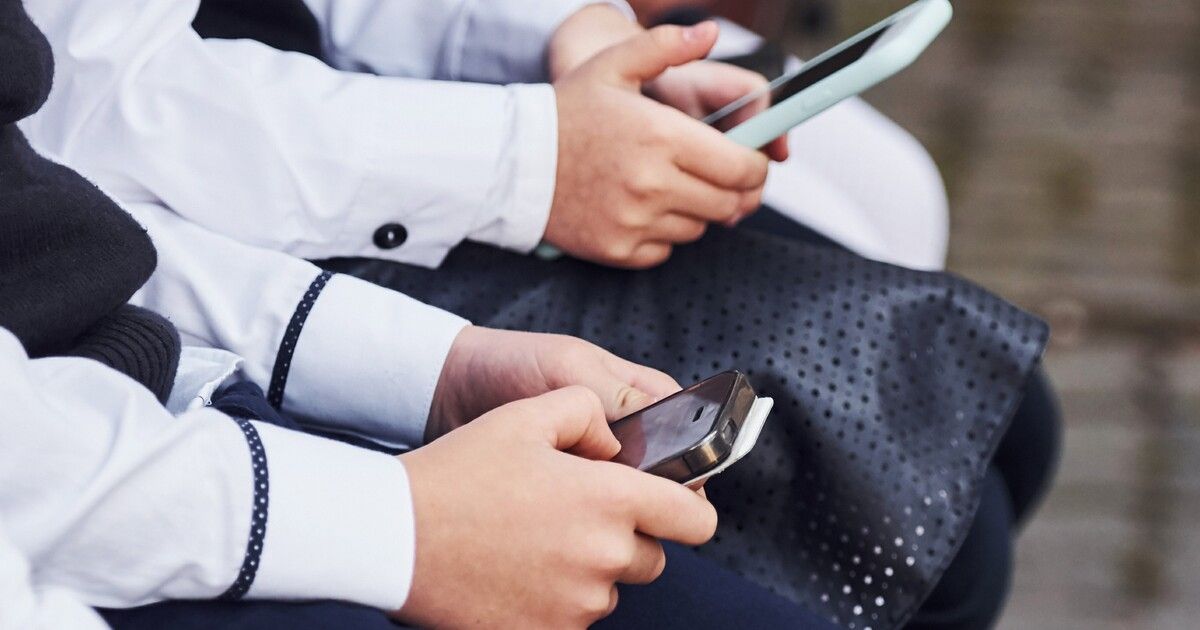 Children use smartphones in school uniforms.