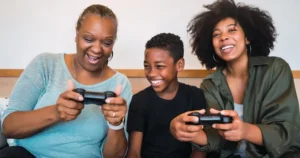 A boy playing video game with his mom and grand mother