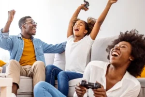 A family plays video games together with the child cheering their success.