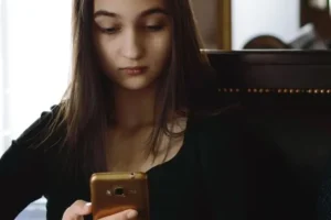 A teen girl looks at her smartphone.