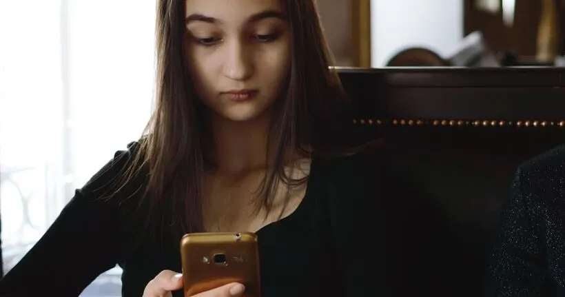 A teen girl looks at her smartphone.