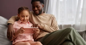 A dad and child look at a tablet together.