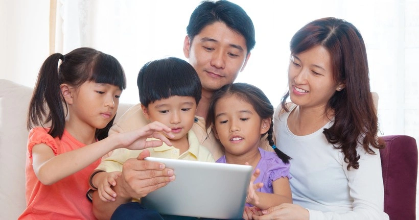 A family of five uses a tablet together.