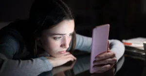 A young girl uses her smartphone but looks worried.