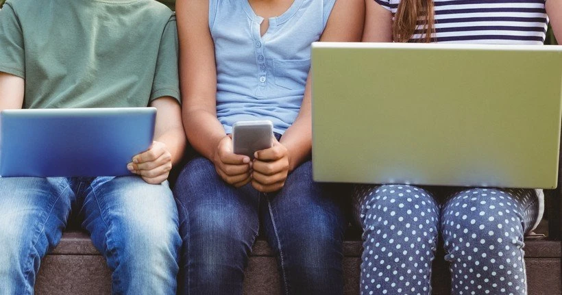 Three children use different connected devices.