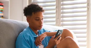 A boy uses his smartphone in his room.